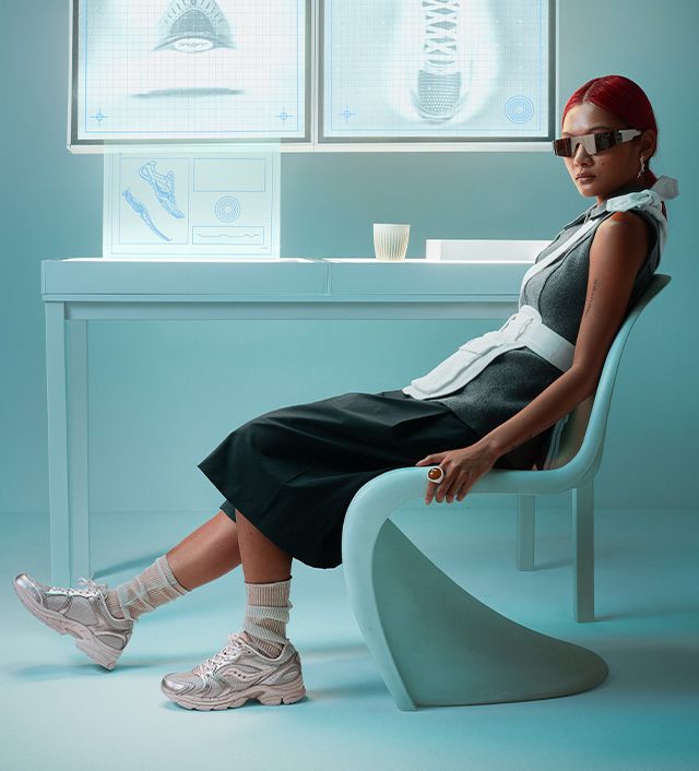 Woman sitting in a retro-futuristic chair wearing a green dress and retro shades.
