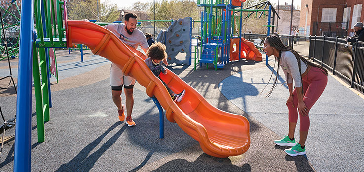 Parents playing with their kid on a playground.