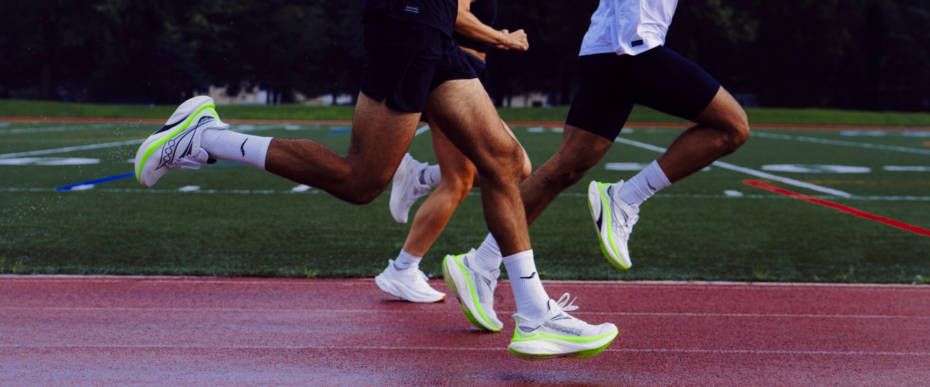 Runners wearing the Saucony Endorphin Speed 6 in white and neon green on an outdoor track.