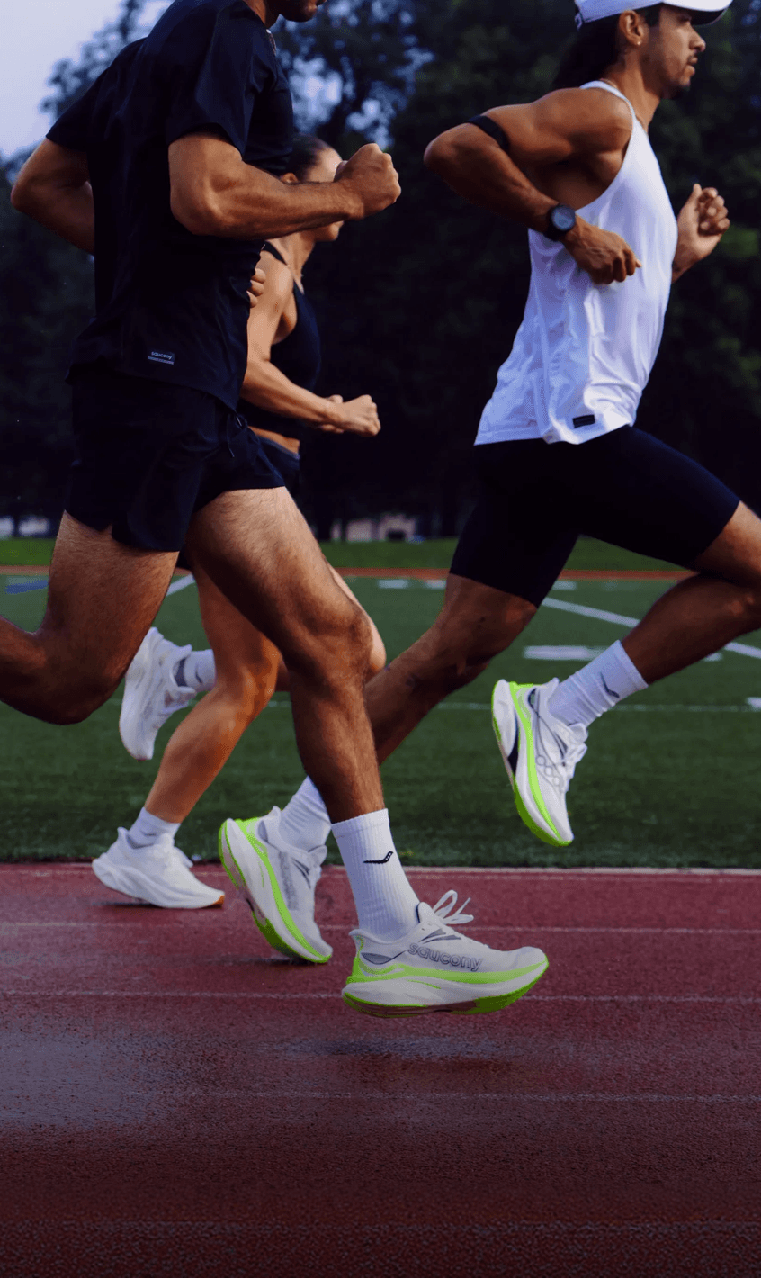 Runners wearing the Saucony Endorphin Speed 6 in white and neon green on an outdoor track.