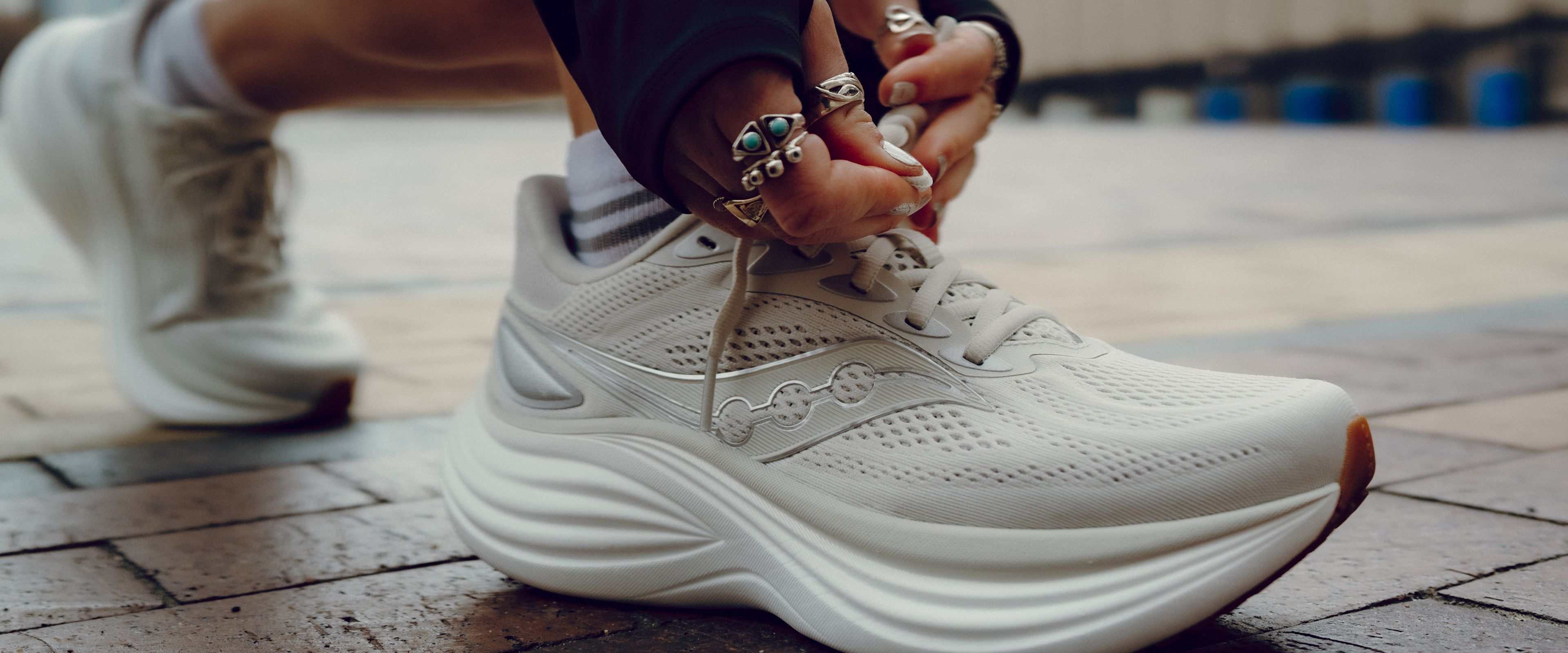 Person kneeling and tying Saucony Triumph 24 shoes.