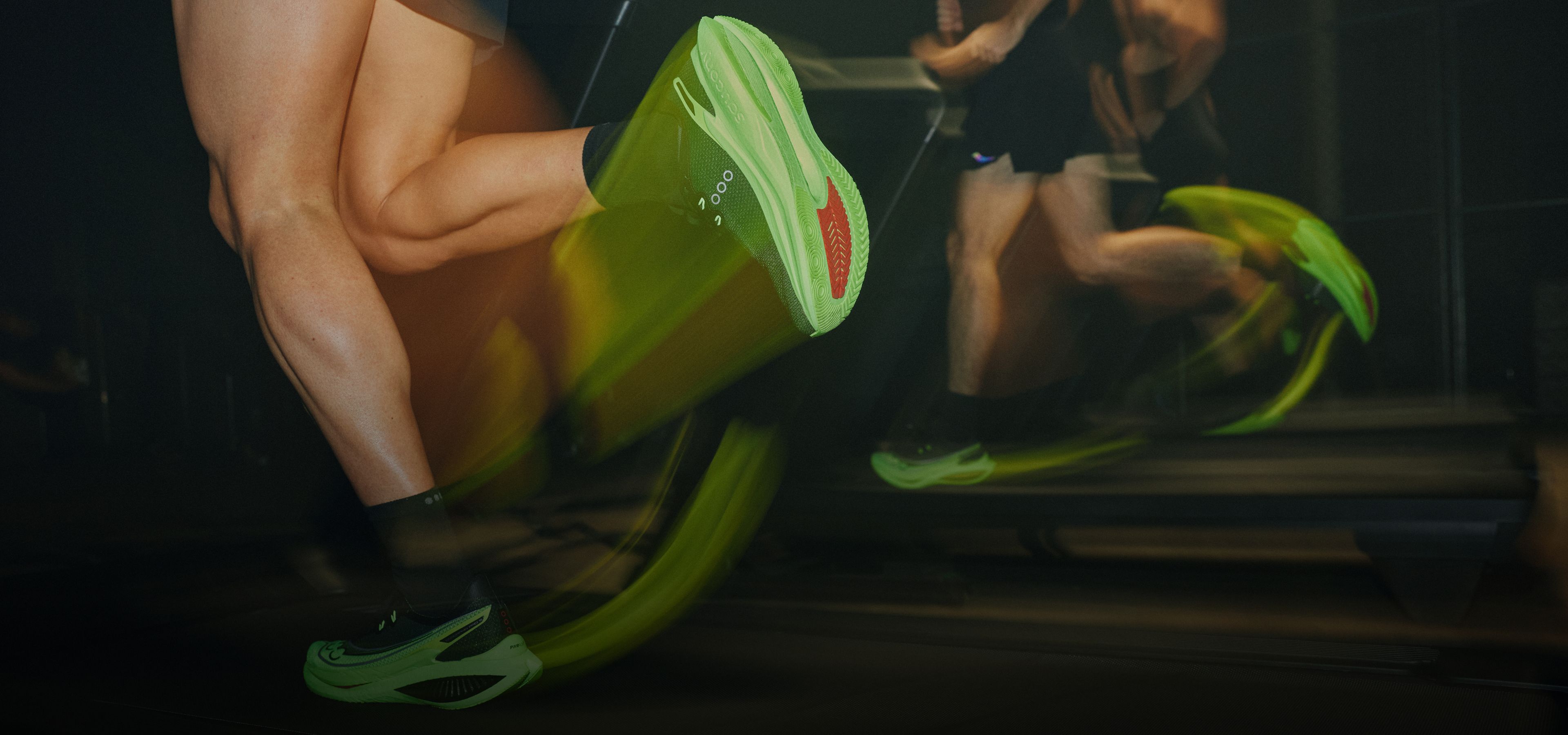 Runners wearing bright green Saucony running shoes on treadmills.